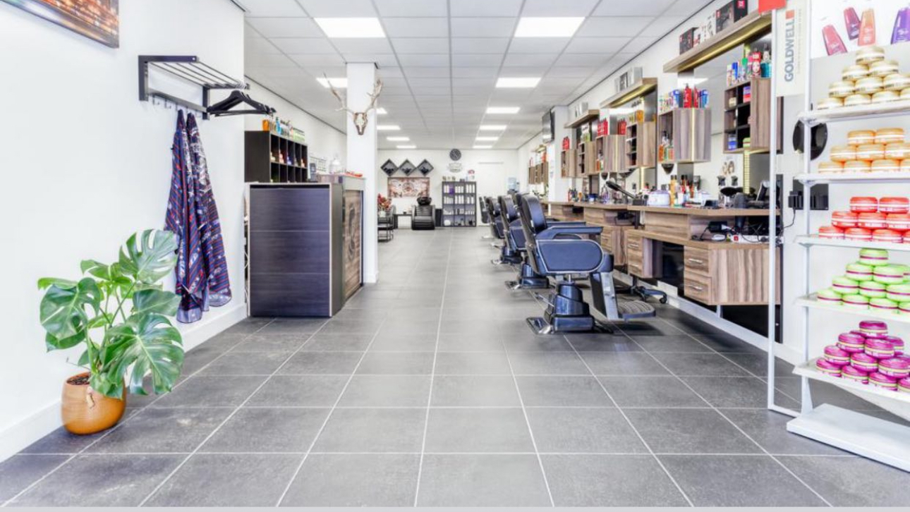 De zaak in de lengte: de kappersstoelen op een rij en rechts de wand met producten