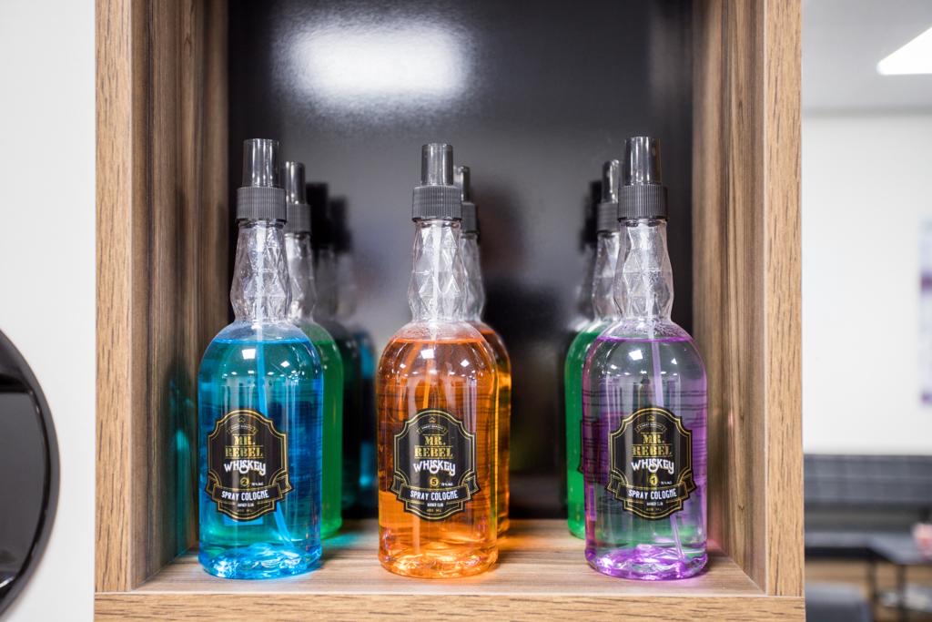 Flessen haartonic in blauw, oranje en paars in een houten vak