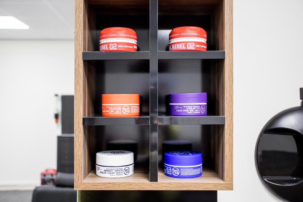 Houten vakkenkast met potten haarwax in rood, wit en paars