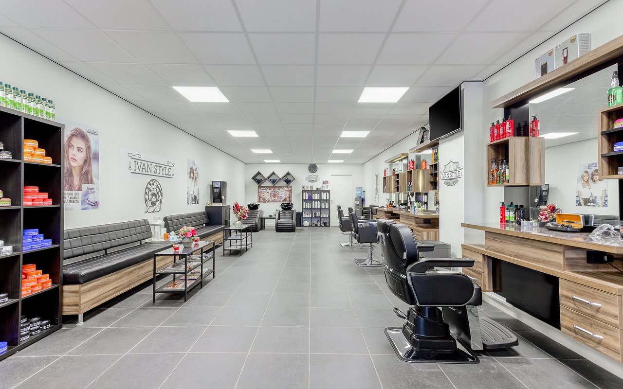 Zwarte wachtbanken langs de wand met vakken vol producten, rechts de kappersstoelen